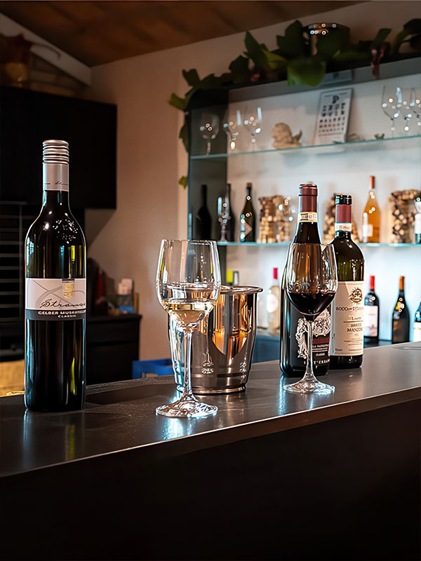 Mehrere Weinflaschen und zwei Gläser mit Weiß- und Rotwein stehen auf einer Bar-Theke im Wyhus Belp